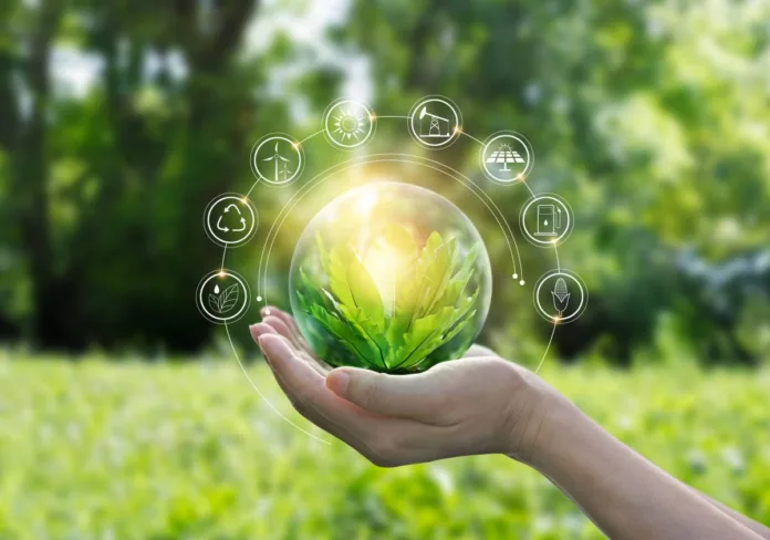 How Sustainable Technology Is Powering the Green Revolution in 2025 A hand holding a glowing green plant inside a transparent globe, surrounded by sustainable energy icons, with a blurred natural background.