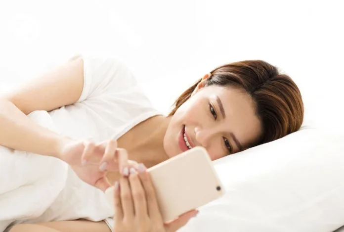 Social-Media-Indulgence Young woman indulging in social media on smartphone while lying in bed — symbolizing digital overuse.