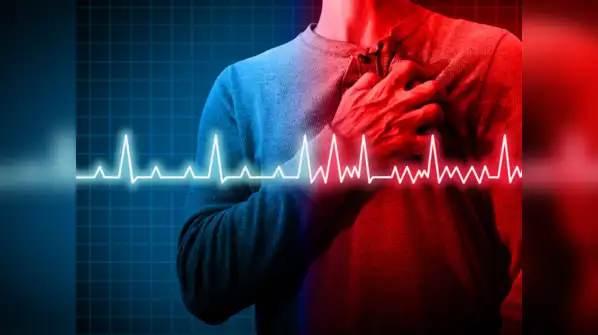 heart-tech Middle-aged man sitting at a desk looking healthy but clutching his chest in slight discomfort, symbolizing early or silent signs of a heart attack.