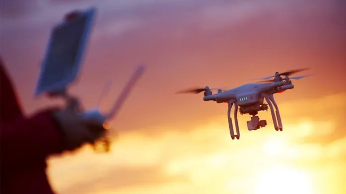 feature-image-Drones-Enhanced-1248x702-1 Autonomous drone flying at sunset with remote controller in hand, symbolizing drone use in logistics and emergency response.